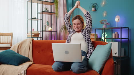 happy woman using laptop receive good news shocked by victory celebrate lottery jackpot win at home