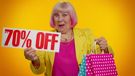 mujer mayor emocionada sosteniendo bolsas de compras y un cartel de 70% de descuento