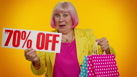 excited senior woman holding shopping bags and a 70% off sign