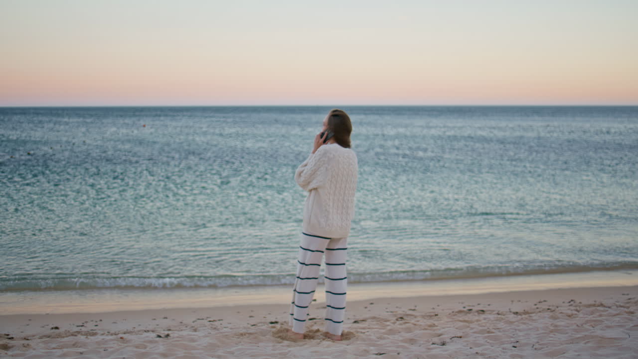 Carefree woman calling beach looking at ripple ocean waves at evening