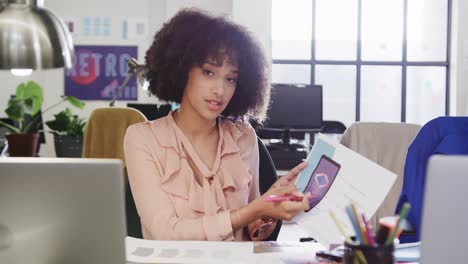 Portrait-of-african-american-female-designer-in-video-call-at-computer-in-casual-office,-slow-motion