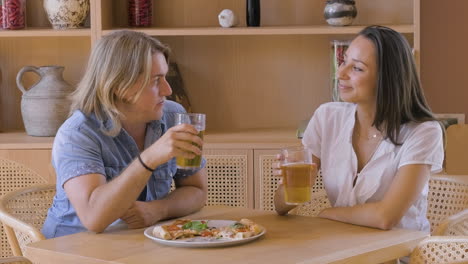 junges paar, das bier trinkt und pizza im restaurant teilt