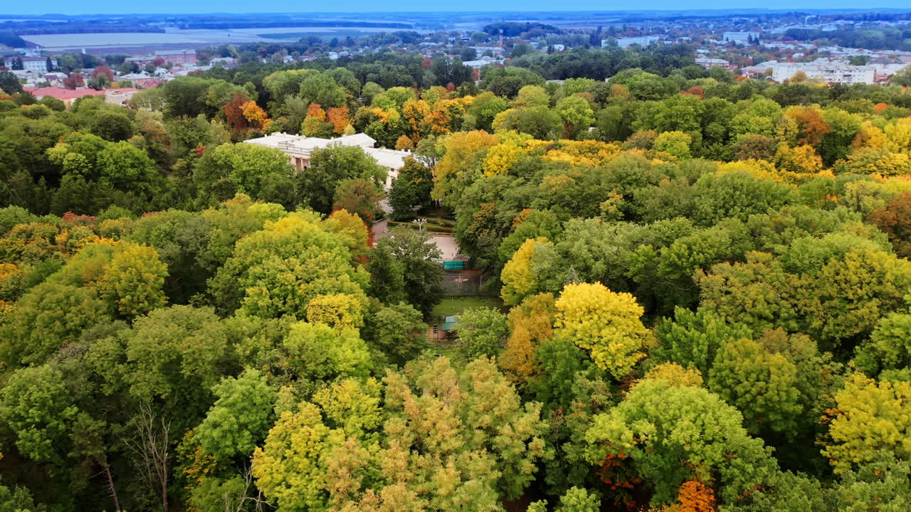 Beautiful trees of different colors growing around the marvelous palace. Cityscape at backdrop in haze.
