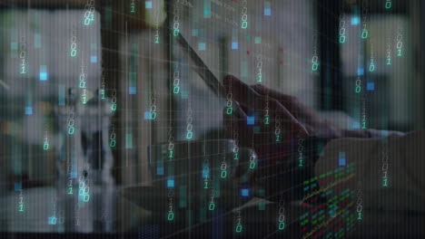 right hand holding smartphone in modern tech workspace, showing binary code and digital charts