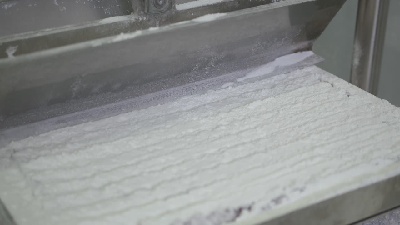 자동화된 공장 기계가 터키 기쁨의 사각형을 자르는 모습