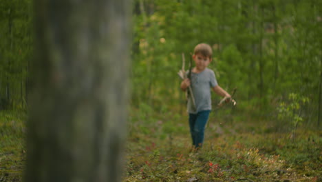 A-boy-collects-and-wears-sticks-for-a-campfire-during-a-hike.-Forest-caster-for-cooking-and-frying-marshmallows