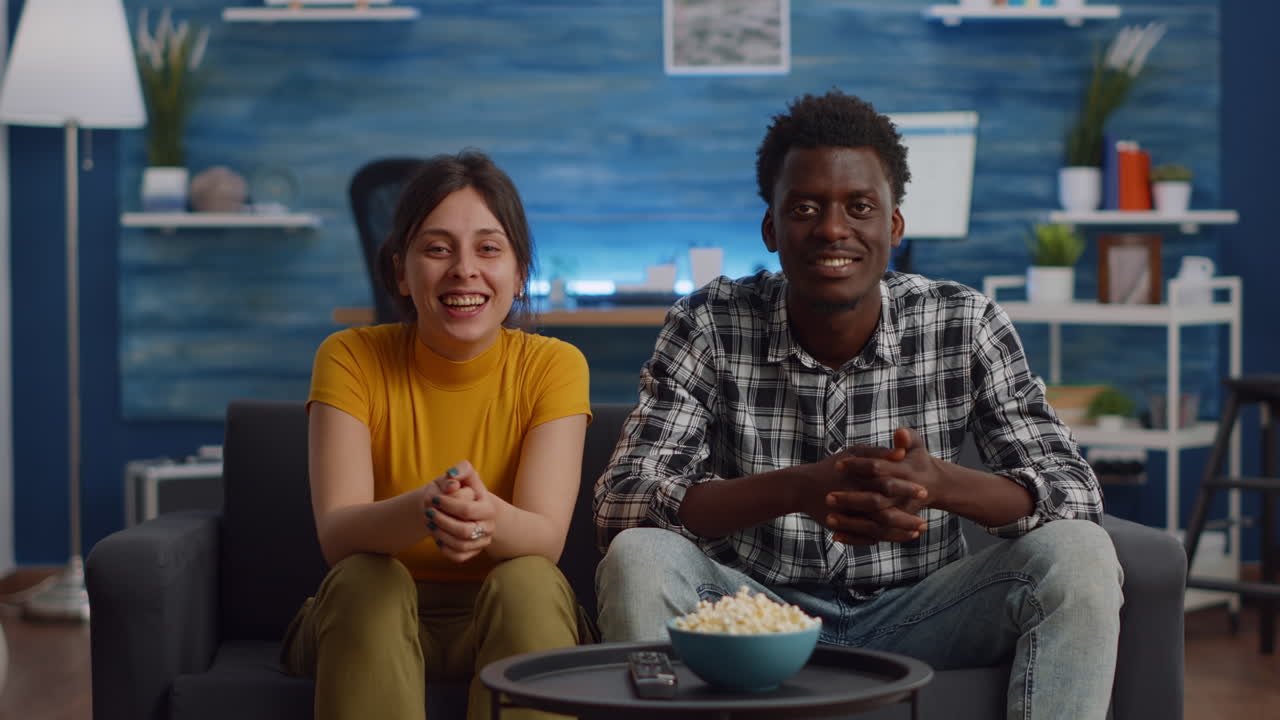 Casal interracial acenando para a câmera em uma videoconferência
