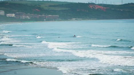 Amplia-Vista-Panorámica-De-La-Gente-Surfeando-Con-Longboard-En-La-Playa-De-Malibu,-Vietnam