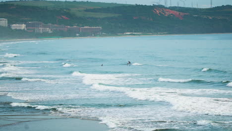 wide panorama view of people surfing with longboard in malibu beach, vietnam