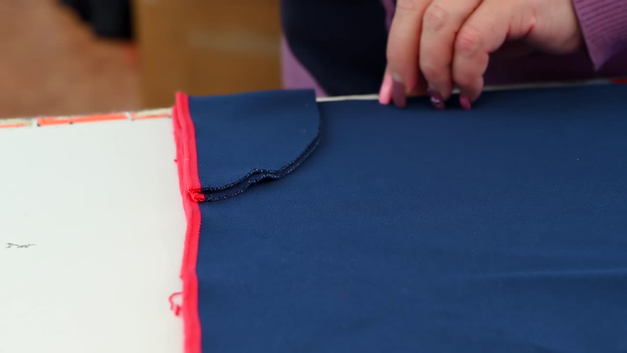 Woman hands cutting a blue knitted fabric with scissors in an workshop. Close up