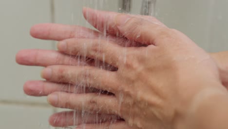 closeup shot white male caucasian hands washing at shower white tile bathroom fingers rubbing water cleaning itself