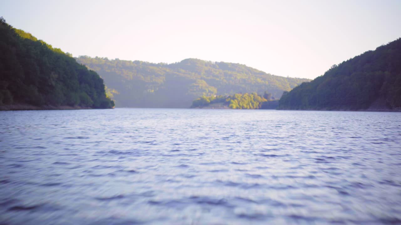 Beautiful smooth lake water, point of view from the front of a speed boat going fast, with green mountains at sunset
