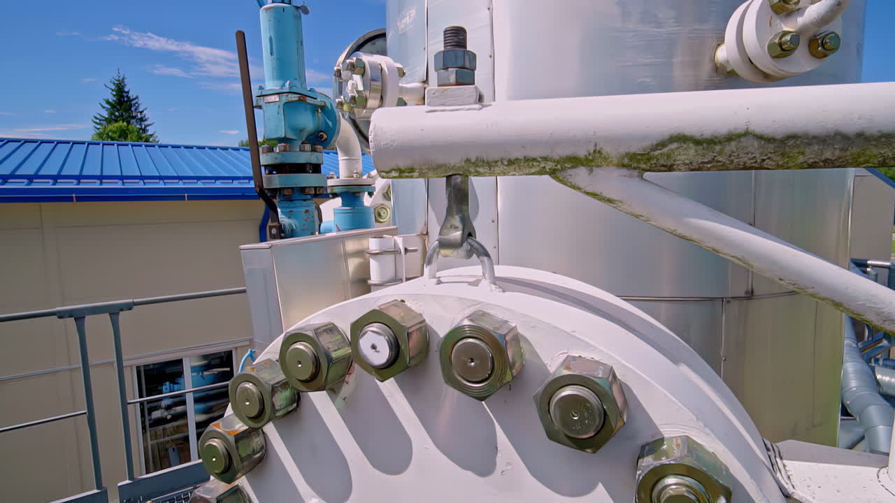A close-up shot details the heavy-duty industrial machinery of a gas pumping facility in Latvia, focusing on the large flanges, bolts, and valves of the natural gas pipeline infrastructure