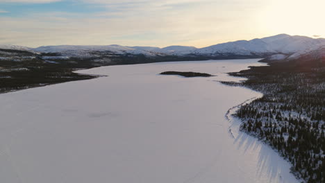 high-definition aerial view of fish lake in whitehorse, yukon, showcasing the untouched snow-covered landscape. the snowy lake and mountains offer a peaceful and pristine winter scene.