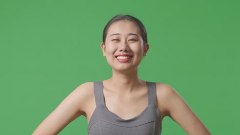 smiling woman in grey sports bra on green screen