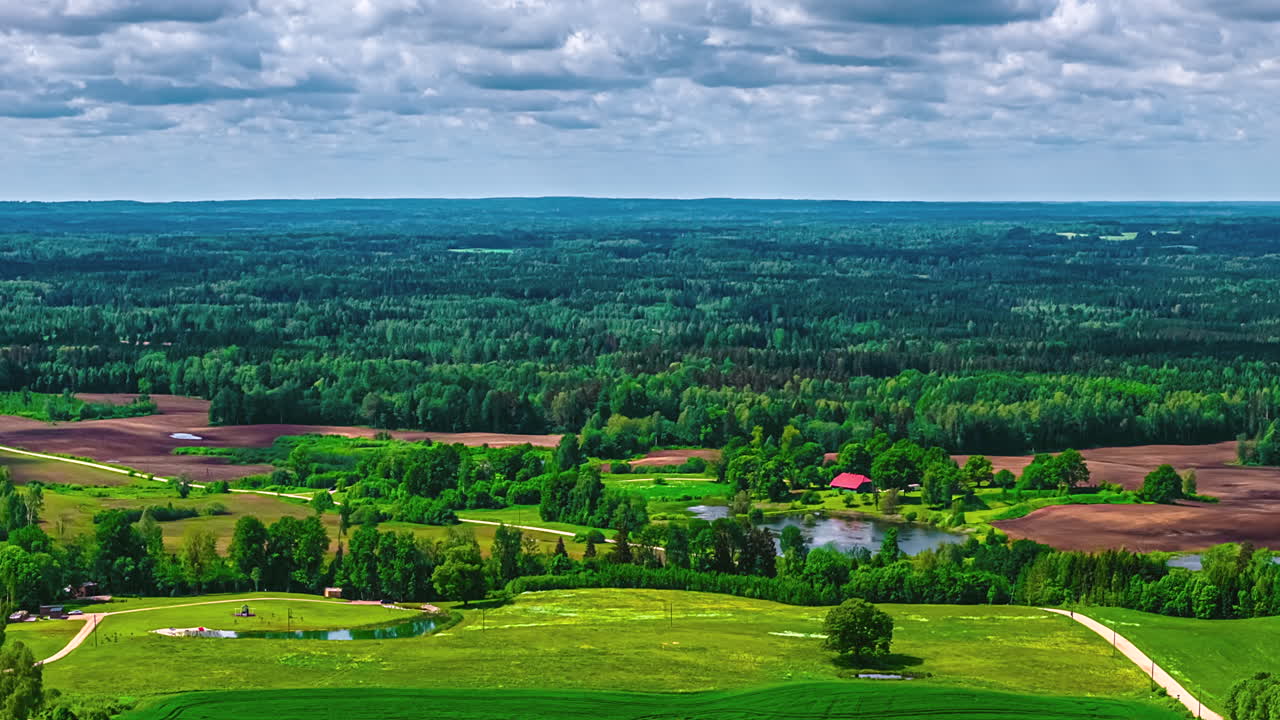 Fast-motion hyperlapse showing forest and fields with dynamic shadows from moving clouds above