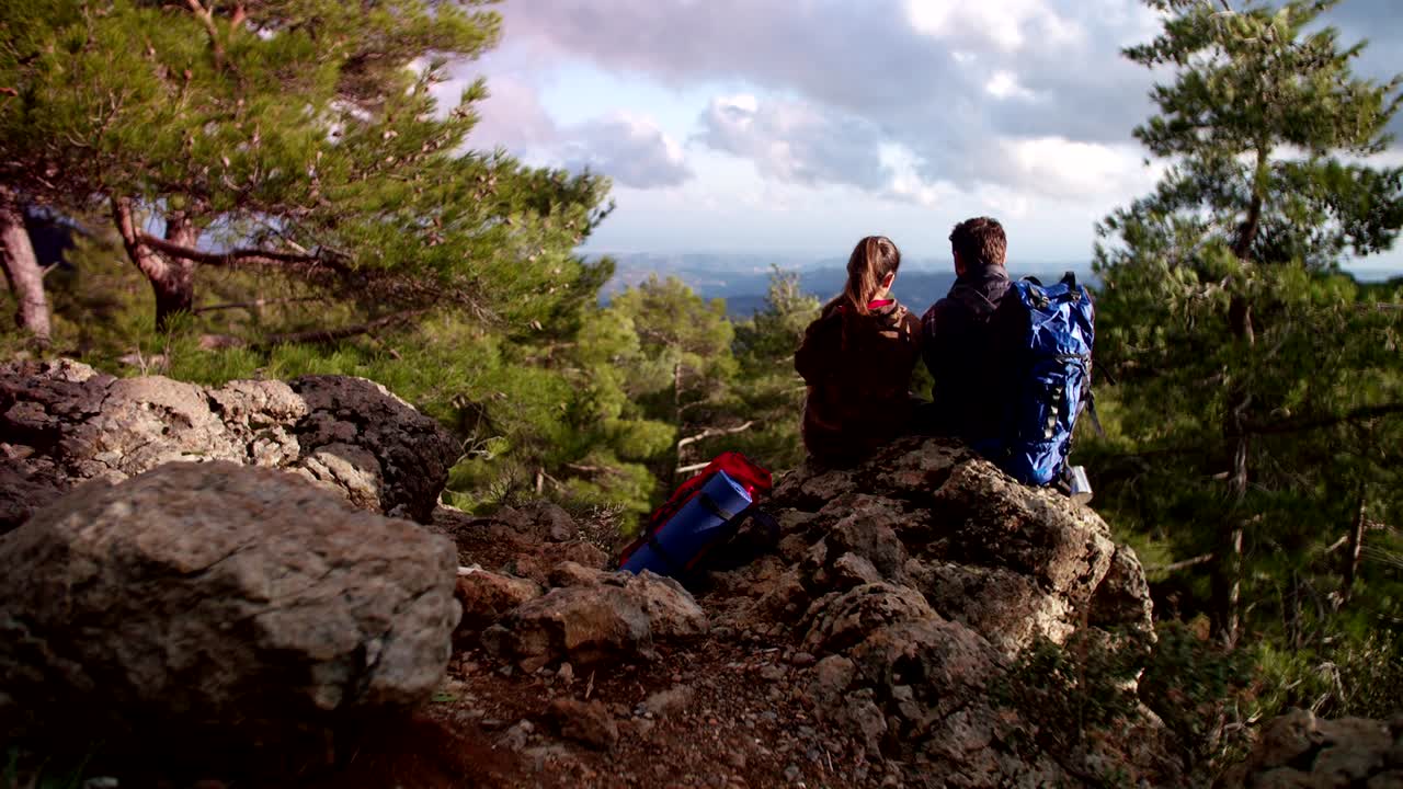Hikers couple sitting on a rock enjoying the mountain view