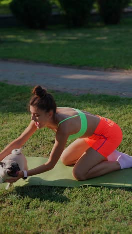 woman practicing yoga with her pug in a park