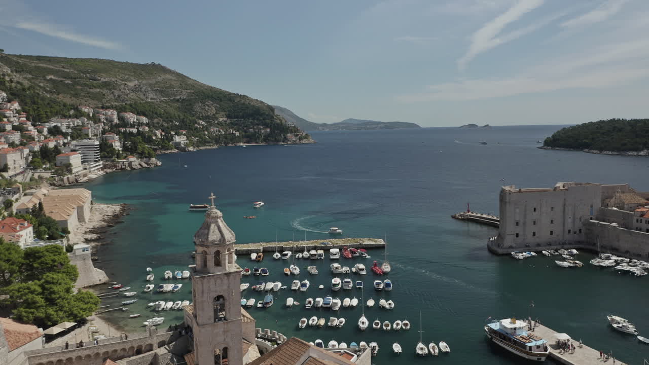 Wide approaching drone shot around Saint Dominic Church bell tower in Old Town Dubrovnik, Croatia with view of Adriatic Sea.