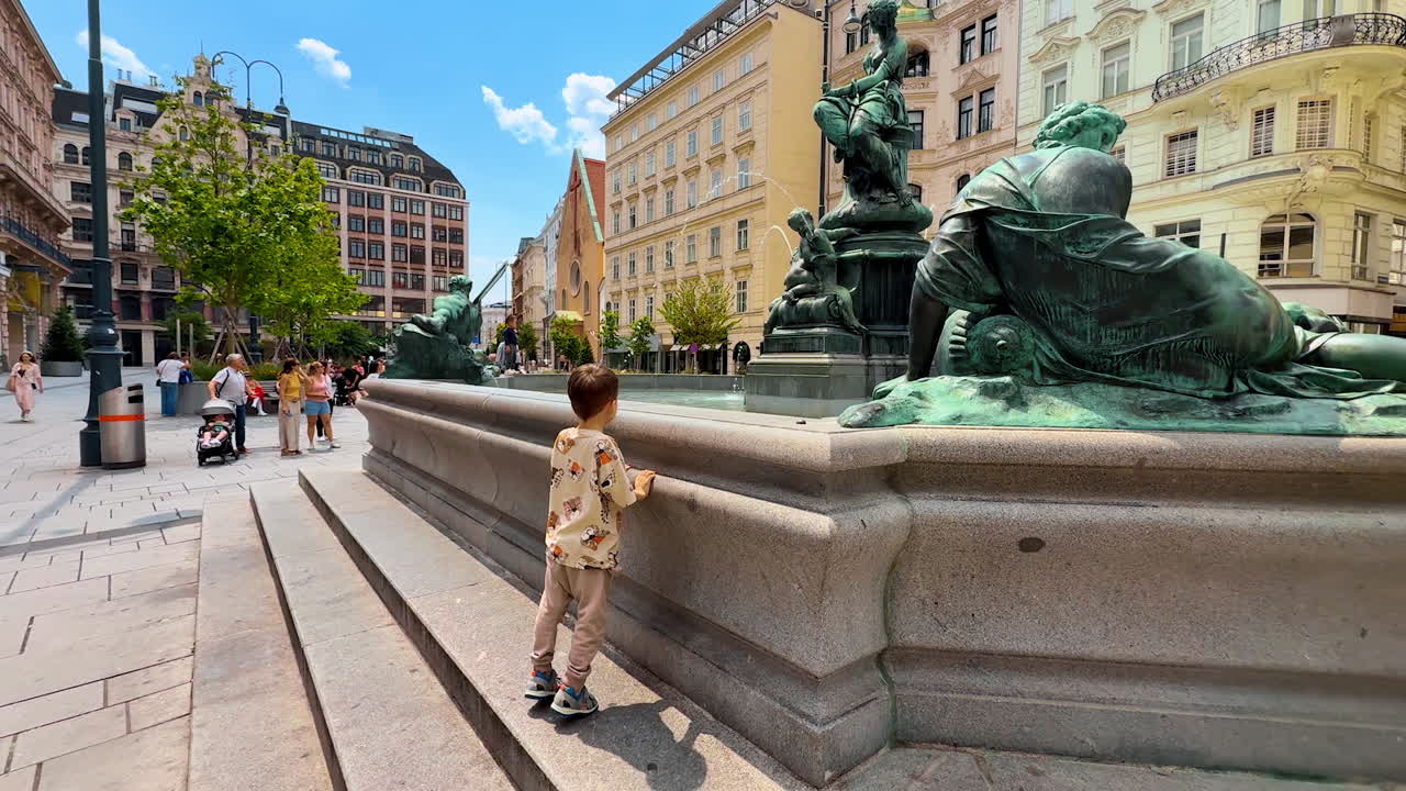 Vienna, Austria - June 9, 2025: Kids playing in Vienna fountains. Children enjoy a sunny day in Vienna, exploring the ornamental fountains while tourists stroll nearby