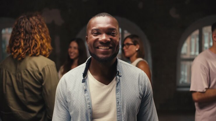 Portrait of a Black man in a blue shirt who is in group therapy in a brick building. Happy man after successful group therapy