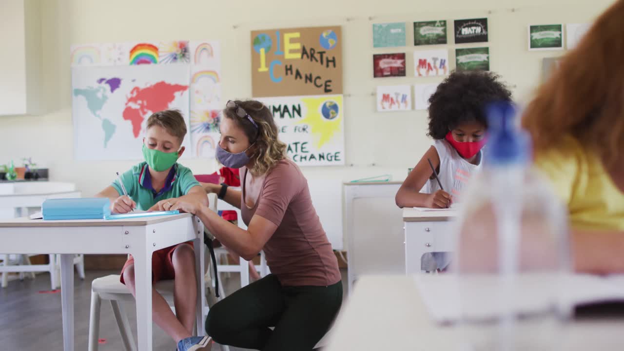 Female teacher wearing face mask teaching a boy in class at school