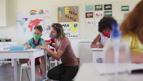 maestra que usa una máscara para la cara enseñando a un niño en clase en la escuela
