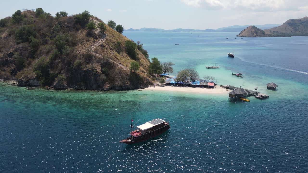 isla de komodo indonesia, vista aérea de drones de la playa de arena blanca, muelle y barcos en un día caluroso y soleado