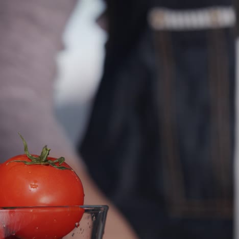 a bowl of tomatoes in the background of a woman's hand