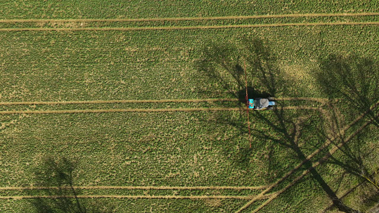 vista aérea de un pulverizador de cultivos rociando fertilizante en el campo de la granja