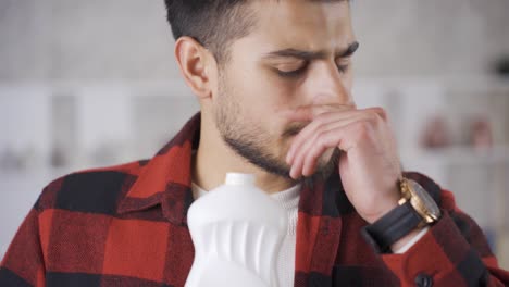 un joven que huele un producto en mal estado se disgusta con el olor.