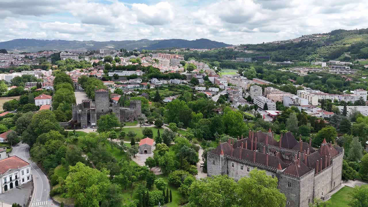 Aerial - Guimarães, Portugal, showcasing the medieval Guimarães Castle and the Palace of the Dukes of Braganza amidst lush greenery