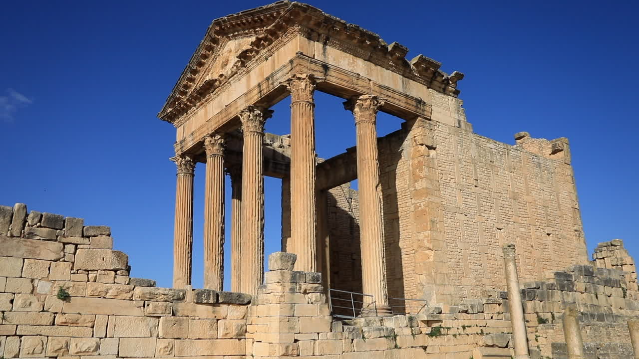 cielo azul claro sobre las ruinas romanas bien conservadas en dougga, antiguas columnas de piedra y architrave