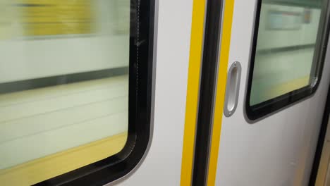 vista de la puerta del tren desde el interior del tren mientras sale de la plataforma - con vista de la plataforma del metro fuera del tren