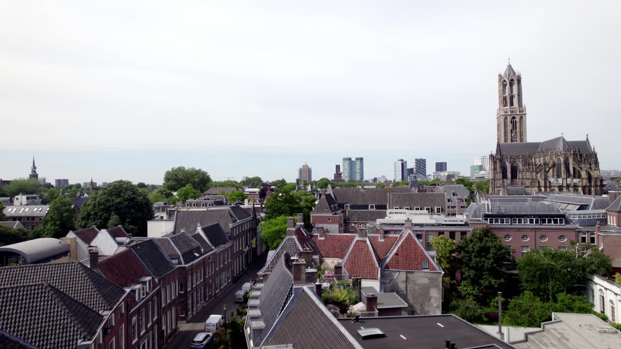 Ascending aerial reveal of historic city center Utrecht with De Dom cathedral tower and the gothic church architecture. Holland religious tourist destination seen from above.