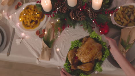 unrecognizable woman putting roast chicken on christmas dinner table 2