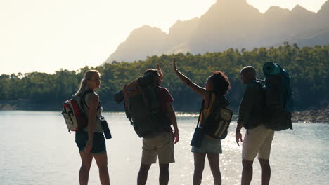 grupo de amigos con mochilas en vacaciones de senderismo mirando el lago y las montañas