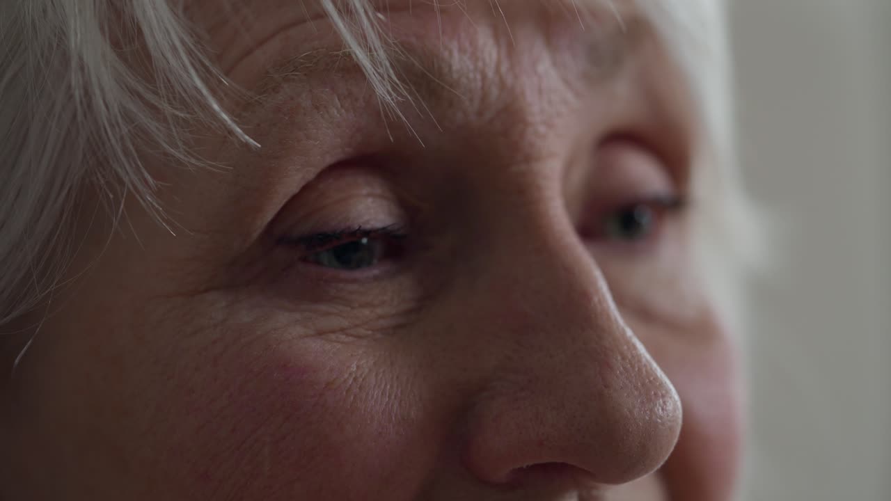 Close-up of an elderly woman's face with wrinkles and closed eyes