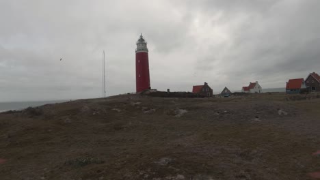 flying towards the old lighthouse (eierland lighthouse) against overcast sky on the coast of texel island in north holland, netherlands. - pov, fpv