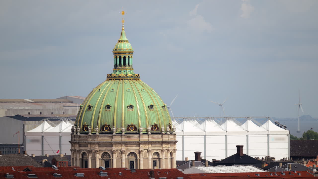 Iconic green copper dome of Frederik's Church rising against a cloudy sky with wind turbines. Copenhagen, Denmark