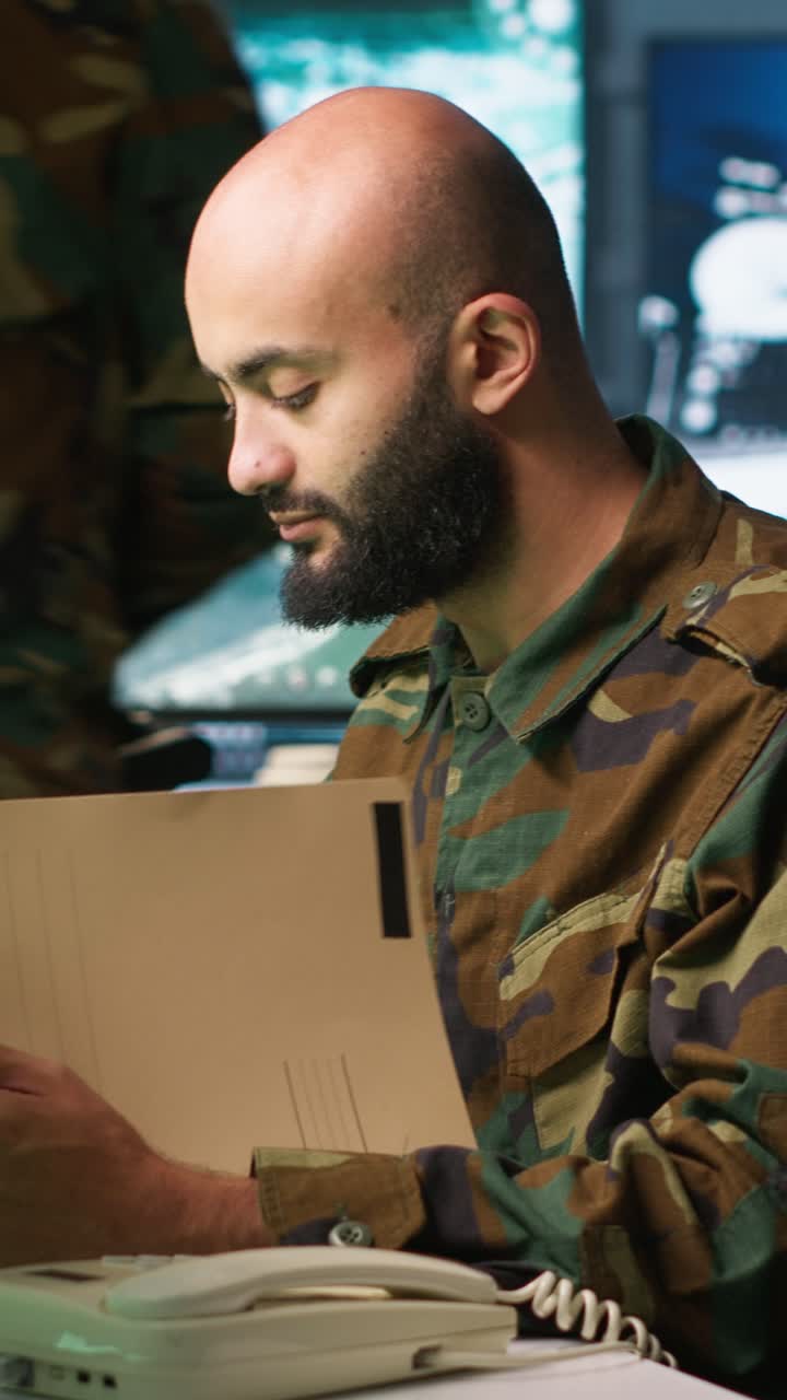 Vertikal video: Militærofficer modtager telefonopkald, mens han gennemgår efterretningsfiler