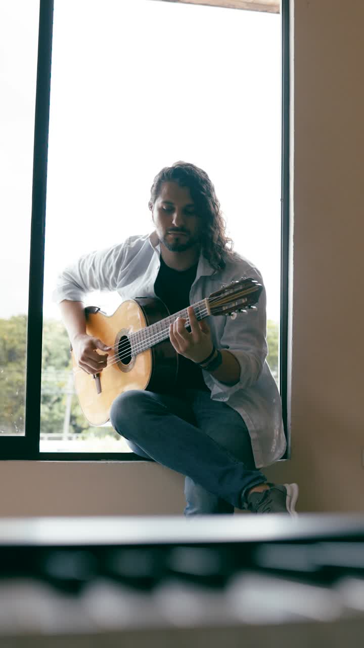 Mand, der spiller guitar ved vinduet