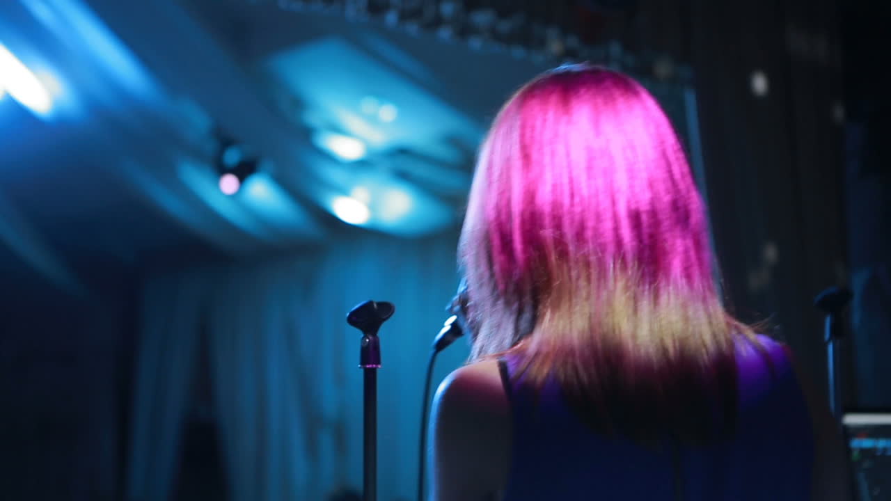 Female vocalist singing in dark stage during the concert