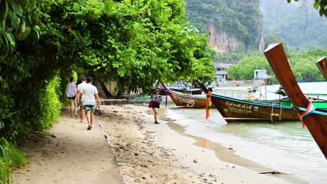 personas caminando cerca de barcos en un camino de arena