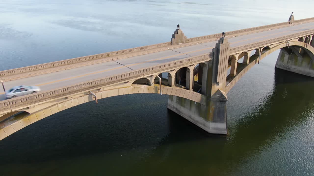 근접 공중 드론 패닝 샷은 펜실베니아의 사스케하나 강에 걸쳐 있는 대형 콘크리트 다리 아치와 건축물을 보여줍니다.