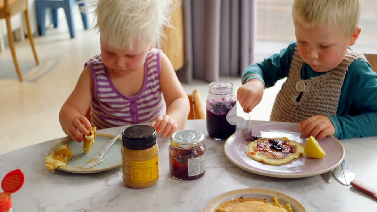 hermanos comiendo panqueques en la mesa de comedor 4k