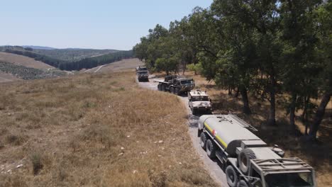 vehículos de soldados del escuadrón del ejército de israel parados en cola en una carretera estrecha, tiro de seguimiento aéreo