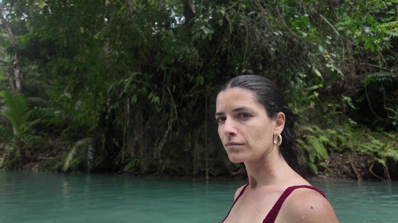 Donna in piedi in una laguna tropicale circondata da vegetazione della giungla.