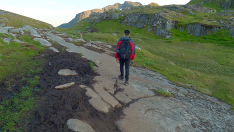 asian male walking in the mountains on lofoten island in northern norway on a nice sunny day, following shot