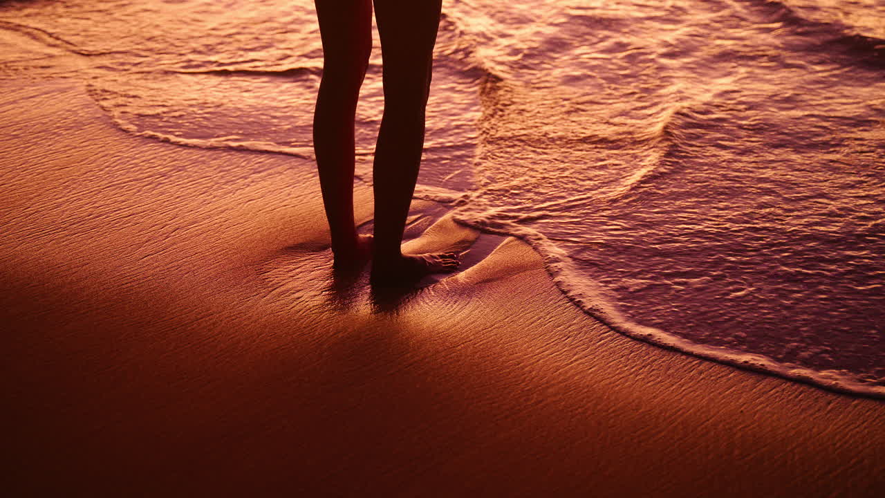 Donna in piedi sulla spiaggia dell'isola di Mahé alle Seychelles durante un bellissimo e caldo tramonto